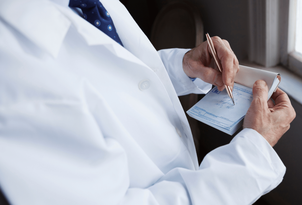 Doctor in white coat writing on a prescription. 